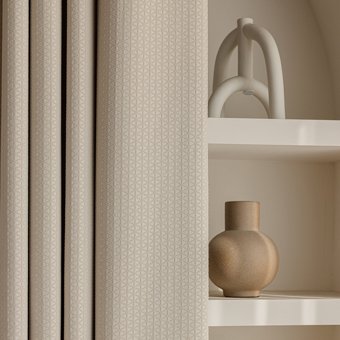 Beige textured diamond pattern curtains with a shelf and decorative vase.
